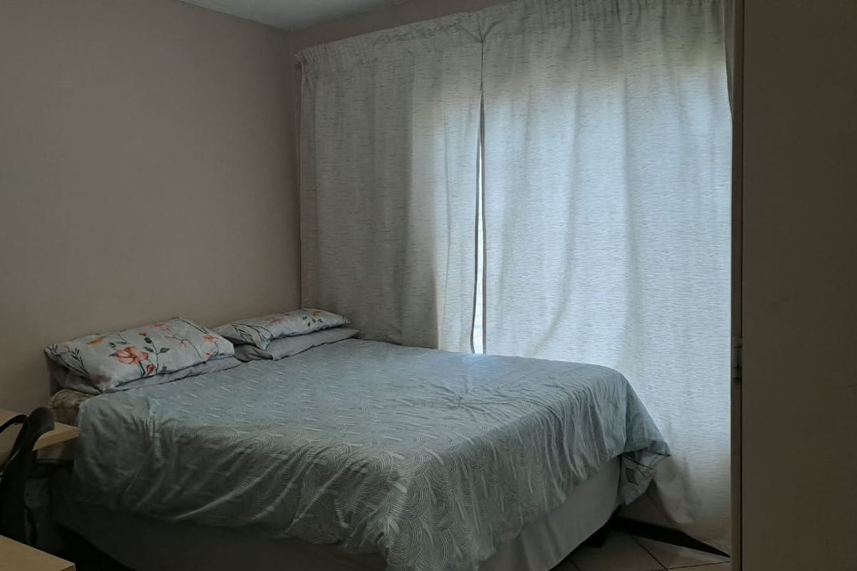 A functional bedroom featuring tiled flooring and floor-to-ceiling curtains, providing a simple and practical living space.