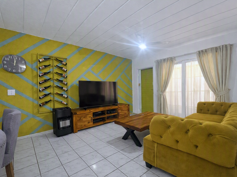 A living room featuring tiled flooring, a ceiling fan, and a sliding glass door providing natural light.