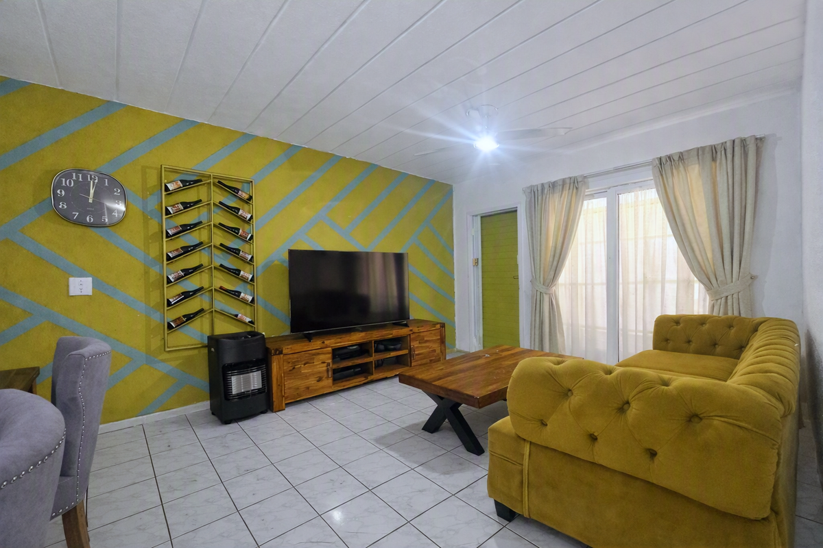 A living room featuring tiled flooring, a ceiling fan, and a sliding glass door providing natural light.