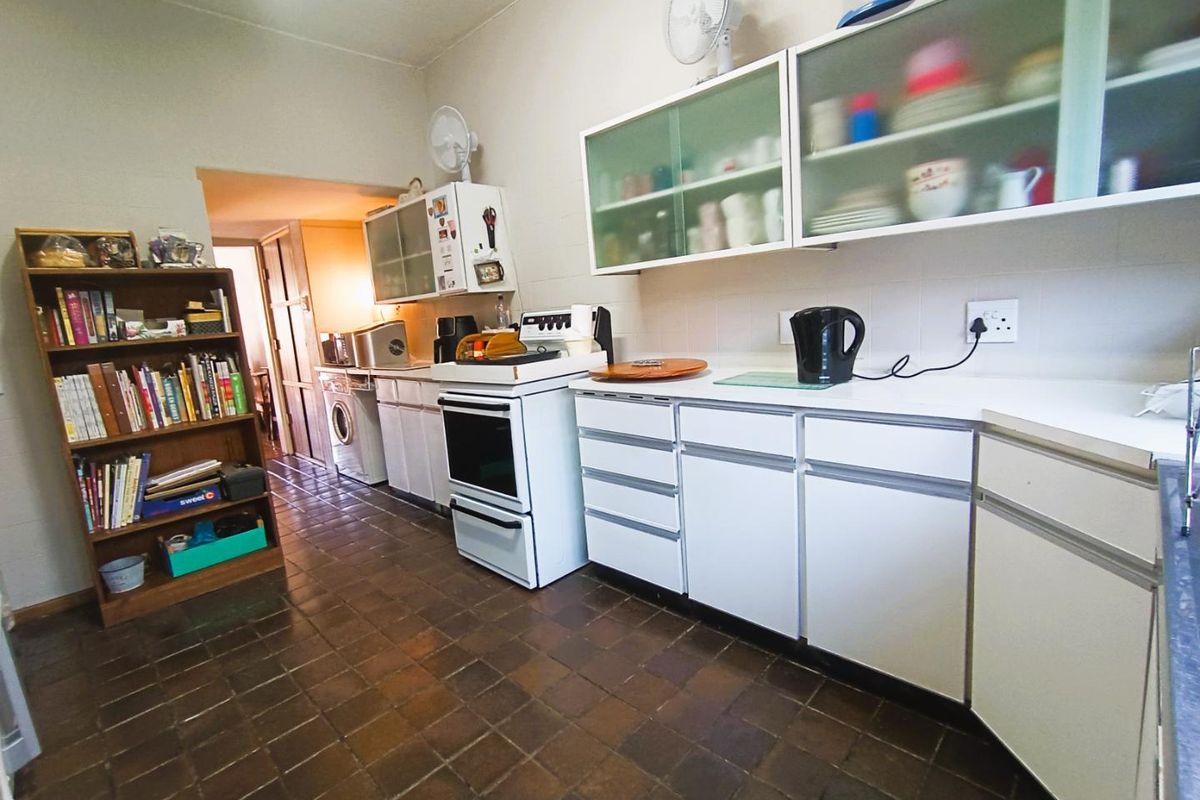 A functional kitchen featuring white cabinetry, tiled flooring, and a built-in stove, offering a practical layout with direct access to an adjacent utility area.