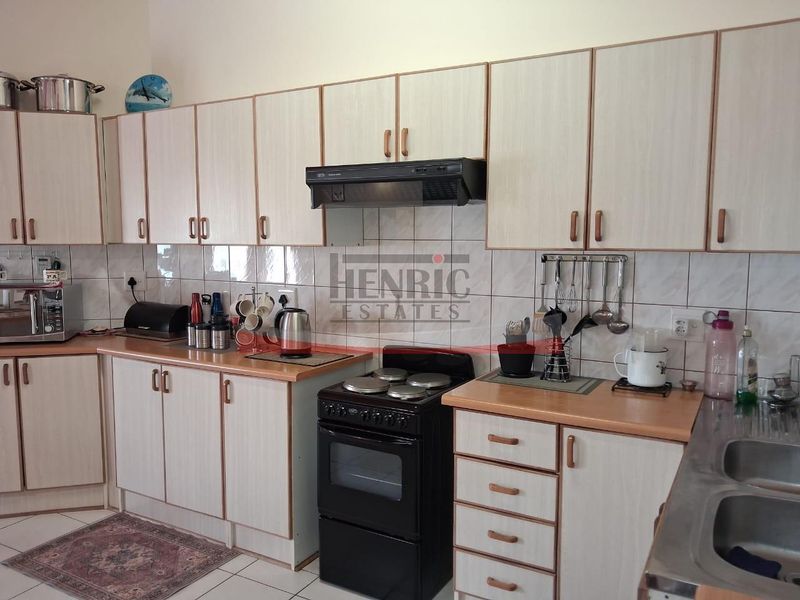A functional kitchen featuring light-toned laminate cabinetry, tiled backsplash, a freestanding stove with extractor fan, and a double bowl sink.