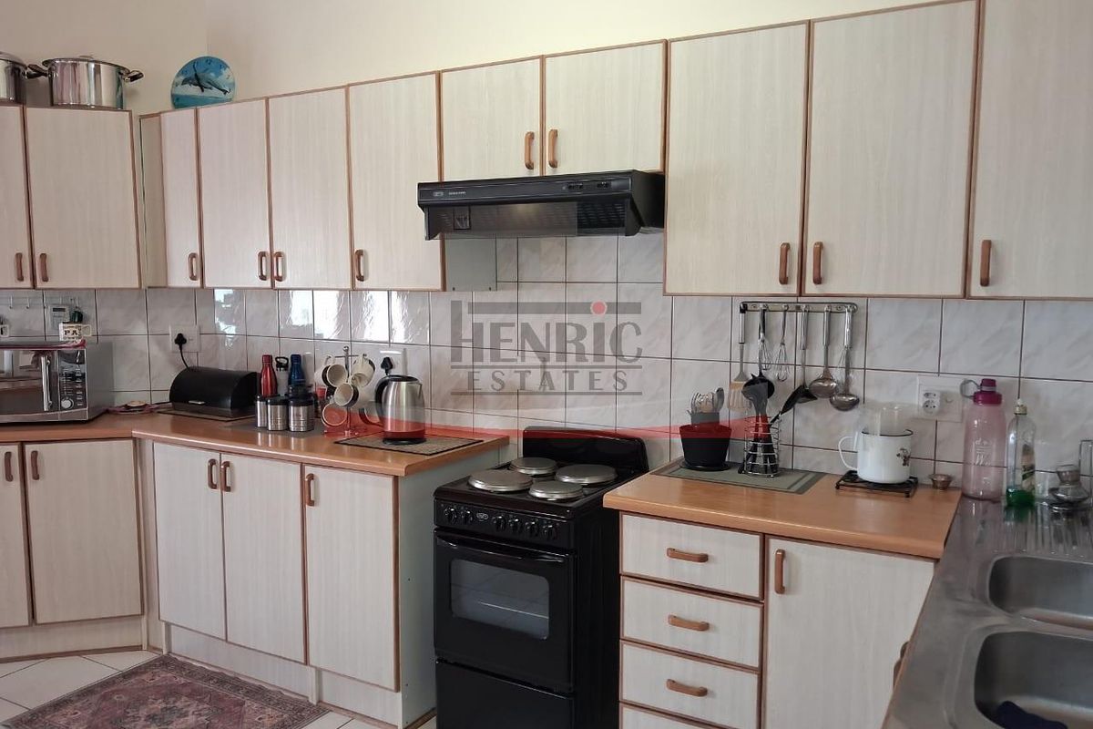 A functional kitchen featuring light-toned laminate cabinetry, tiled backsplash, a freestanding stove with extractor fan, and a double bowl sink.