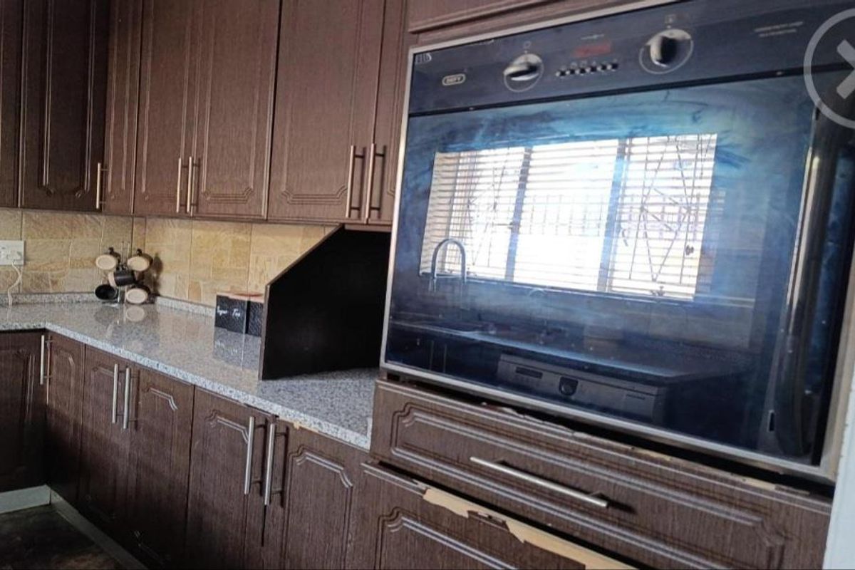 Kitchen featuring dark wood-look cabinetry, granite-style countertops, and a built-in oven, providing a functional workspace with classic design elements.