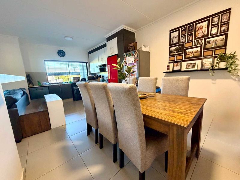 Open-plan living and dining area featuring tiled floors and a functional kitchen with built-in cabinetry.