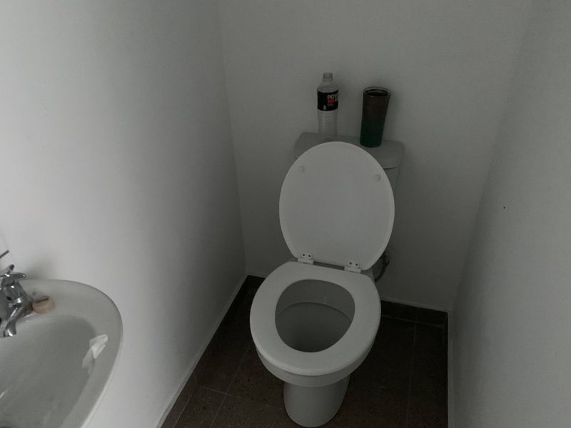 A compact bathroom featuring a standard toilet and a small wall-mounted washbasin with tiled flooring.