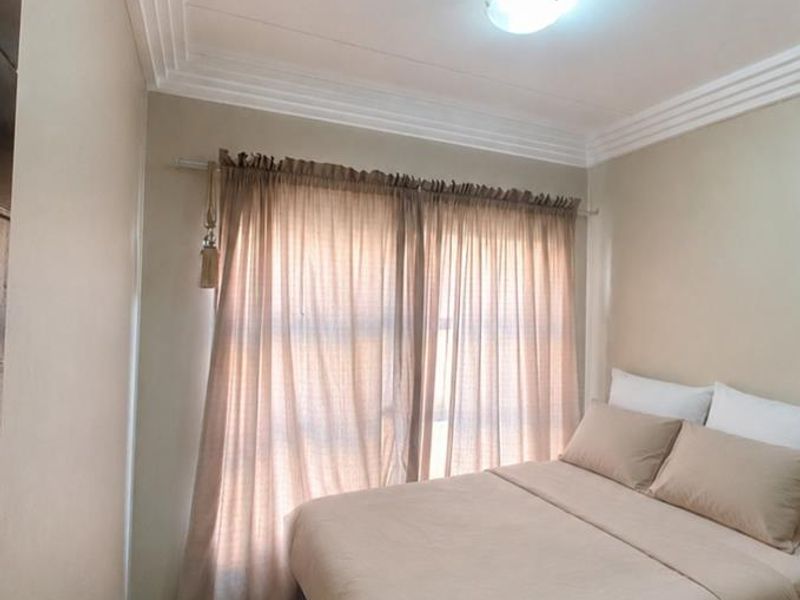 A compact bedroom featuring neutral wall tones, tiled flooring, and decorative ceiling cornicing, providing a simple and functional living space.