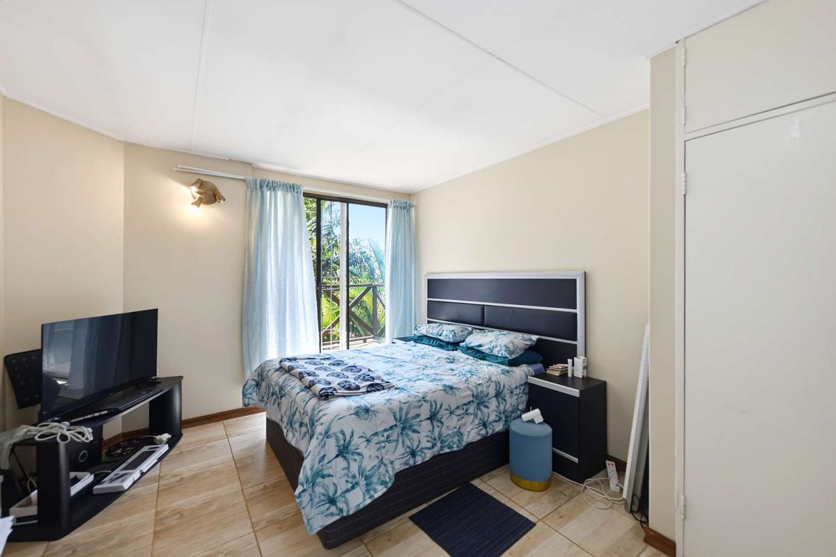 A bedroom featuring tiled flooring, a built-in wardrobe, and a sliding glass door providing access to an outdoor area.