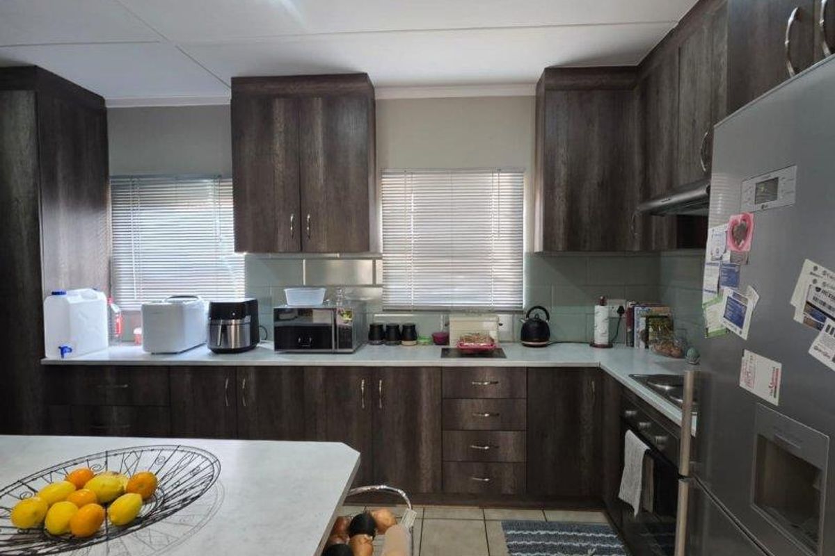 A functional kitchen featuring dark wood-grain cabinetry, light-toned countertops, tiled flooring, and recessed ceiling lighting.