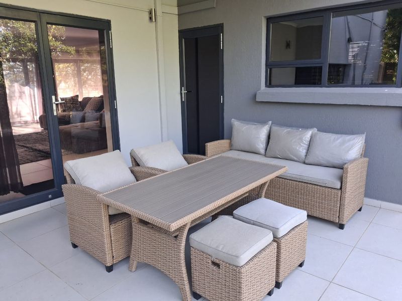A well-maintained covered patio area featuring tiled flooring, modern aluminium sliding doors, and large windows, providing a seamless transition to the interior living space.
