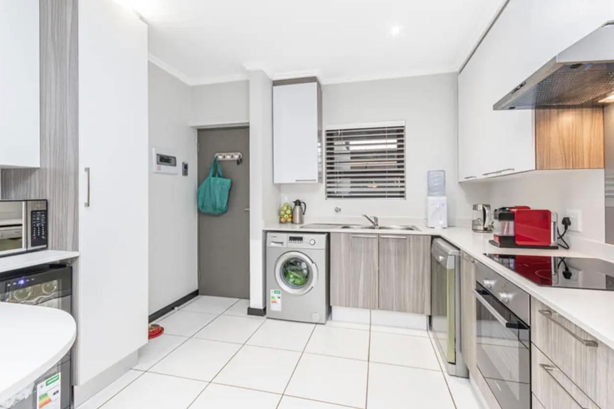 Modern kitchen featuring sleek cabinetry, stone countertops, integrated appliances, and tiled flooring, offering a clean and functional workspace.