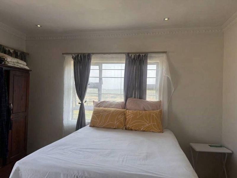 A standard bedroom featuring recessed downlights, decorative cornice, and a window fitted with security bars.