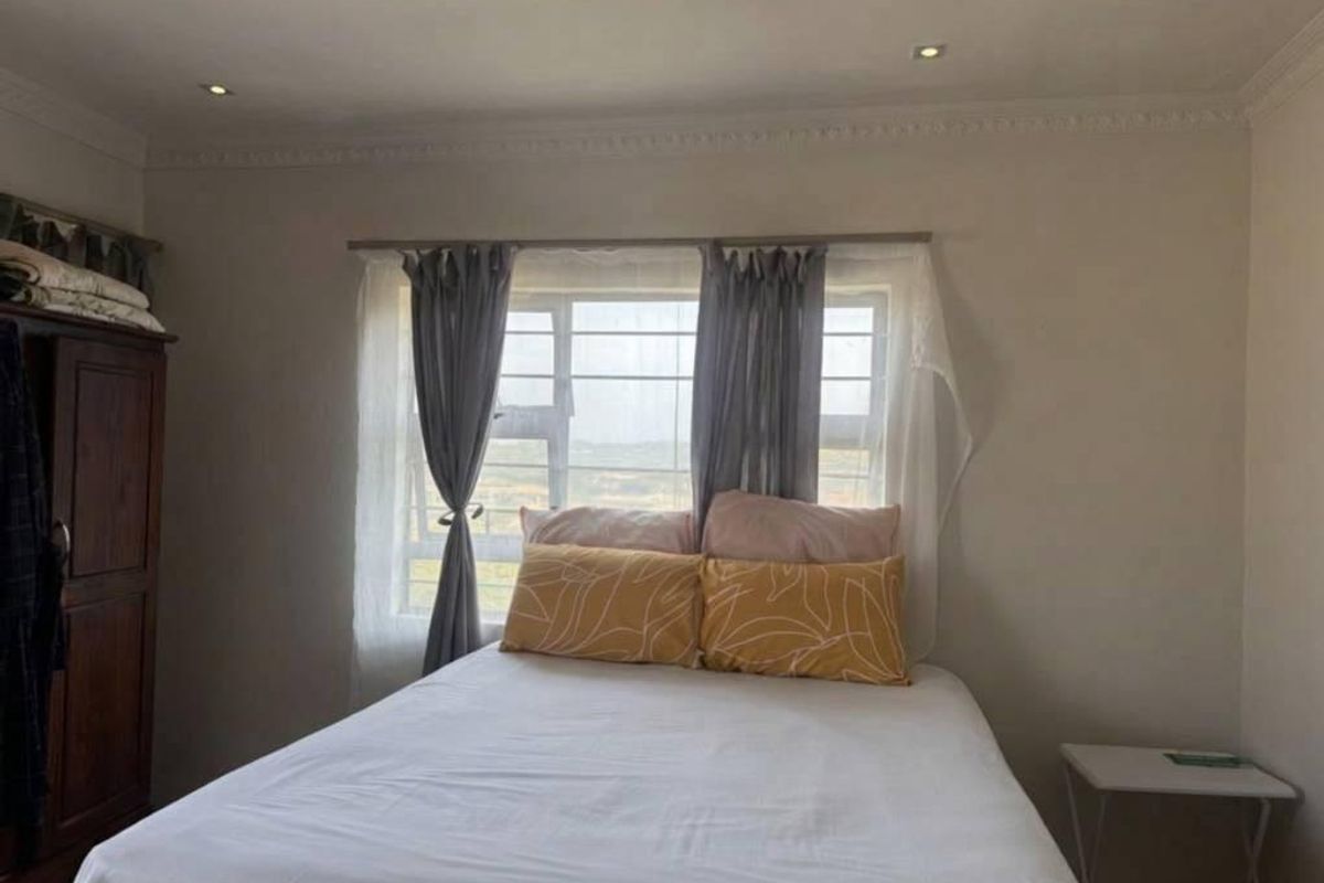 A standard bedroom featuring recessed downlights, decorative cornice, and a window fitted with security bars.