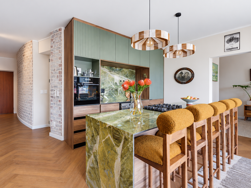 Modern kitchen featuring a striking green stone island, integrated appliances, custom cabinetry, and elegant herringbone flooring, creating a sophisticated and functional culinary space.