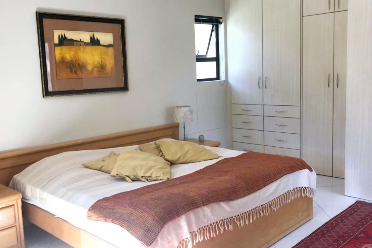 A well-lit bedroom featuring built-in wooden cabinetry, tiled flooring, and a window providing natural light.