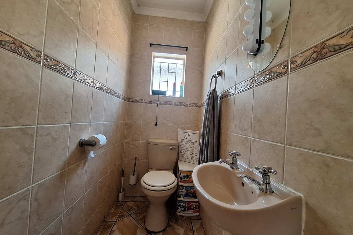 A compact guest bathroom featuring floor-to-ceiling ceramic tiling, a pedestal basin, and a standard toilet.
