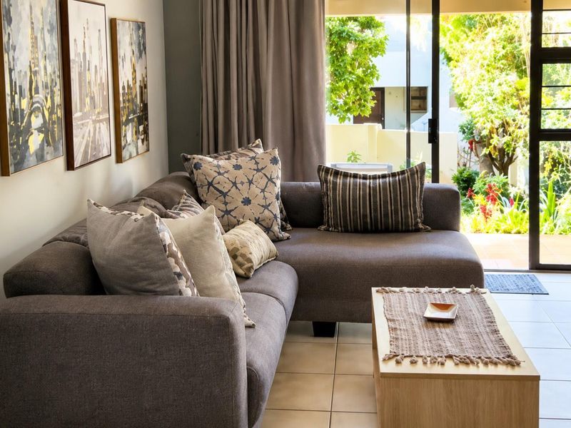 A comfortable living room featuring tiled flooring and a large sliding glass door that provides direct access to the outdoor patio and garden area.