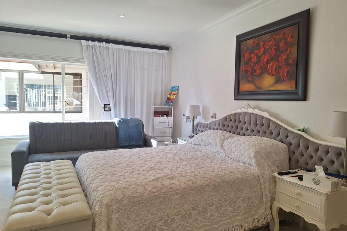 A spacious bedroom featuring recessed downlighting, coving, and a large sliding glass door providing access to the exterior.
