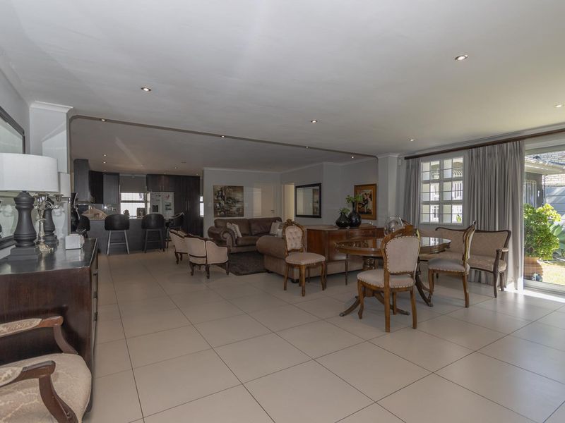 Spacious open-plan living and dining area featuring neutral tiled flooring, recessed lighting, and seamless flow to the outdoor patio through large sliding glass doors.