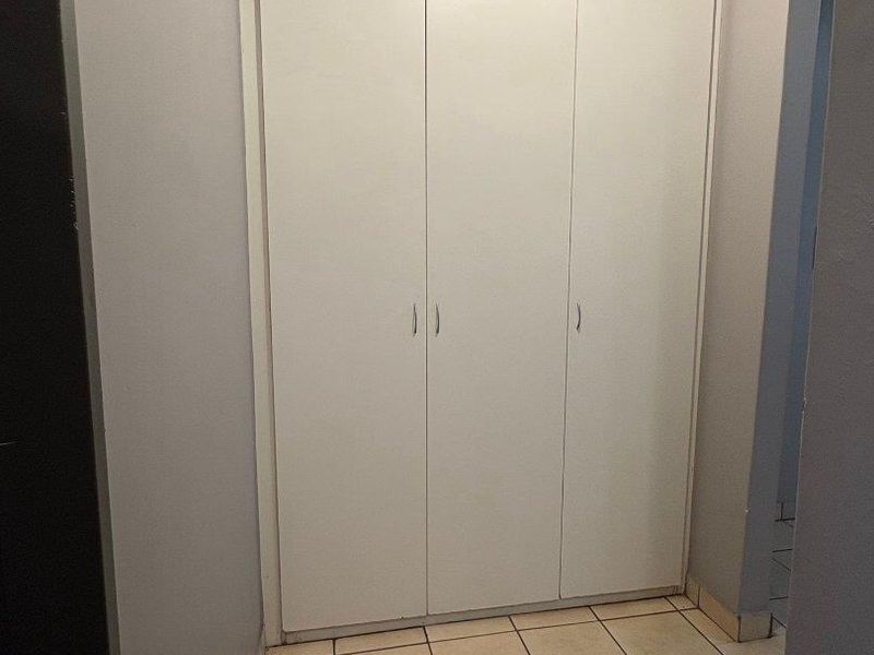 A functional hallway featuring built-in storage cupboards and tiled flooring, providing practical storage space within the apartment.