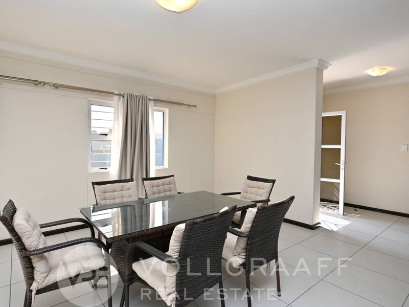 A bright dining area featuring neutral walls, tiled flooring, and classic cornicing, providing a clean and functional space for family meals.