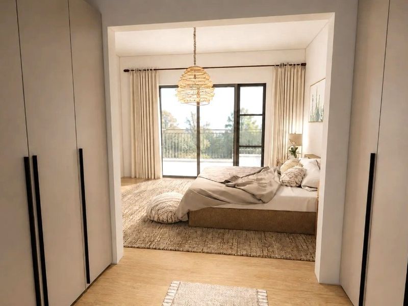 Spacious bedroom featuring built-in wardrobes, timber flooring, and a sliding glass door providing direct access to a private balcony.