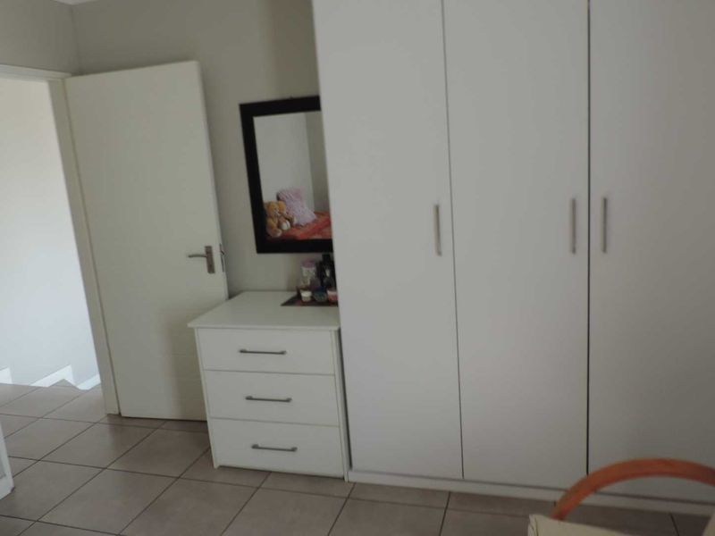 Bedroom featuring built-in cupboards and neutral tiled flooring, providing a functional and clean living space.