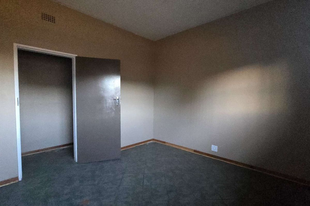 An empty bedroom featuring neutral wall tones, carpeted flooring, and a built-in doorway leading to an adjacent space.