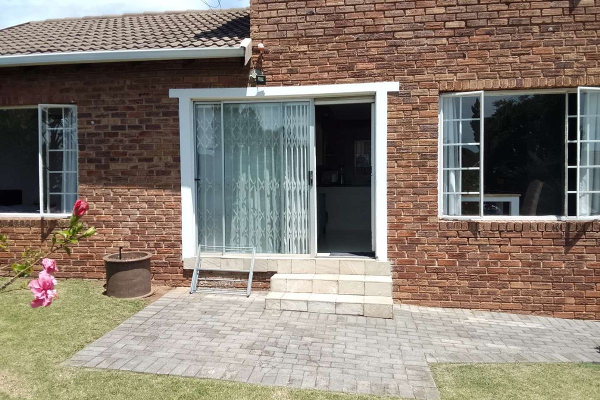 Rear exterior view of the townhouse featuring a brick facade, paved patio area, and sliding door access to the interior living space.