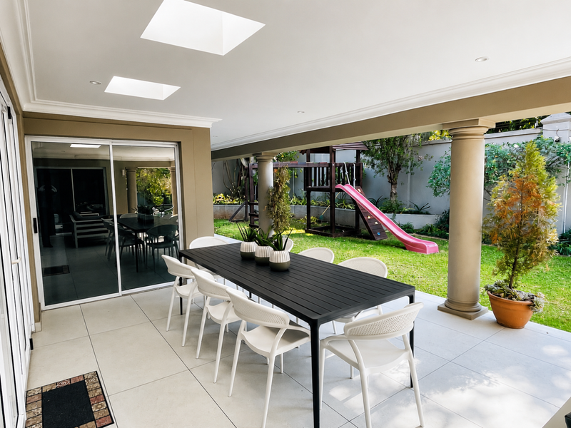 A spacious covered patio featuring tiled flooring, recessed lighting, and skylights, providing seamless indoor-outdoor flow through large sliding glass doors.