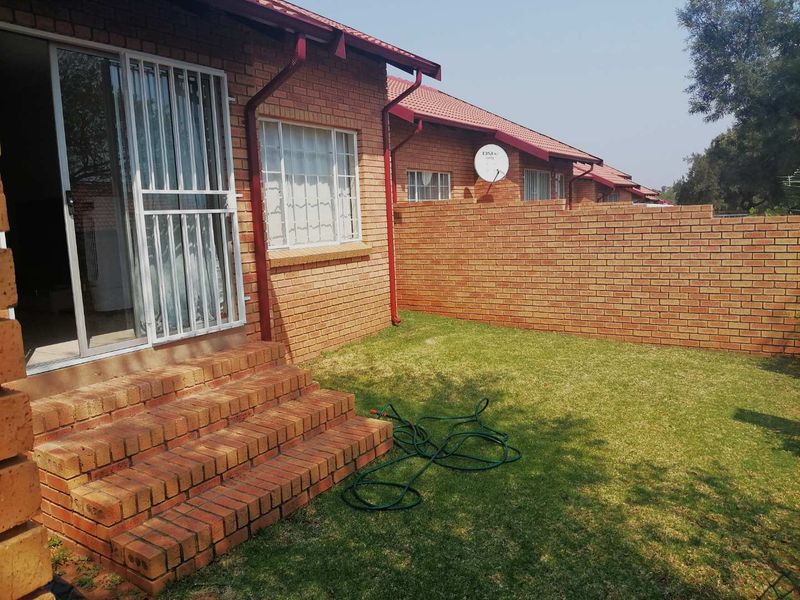 A private rear garden area featuring a brick facade, sliding door access with security gate, brick steps, and a perimeter boundary wall.
