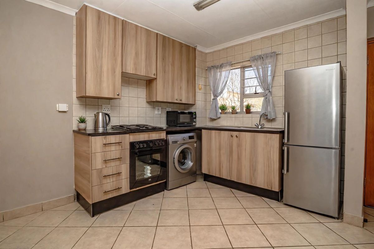 A functional kitchen featuring light wood-look cabinetry, tiled backsplash, built-in oven with gas hob, and dedicated space for a washing machine.