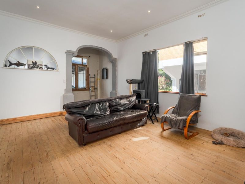 Spacious living room featuring original hardwood flooring, recessed lighting, and a distinctive architectural archway leading to an adjacent area.