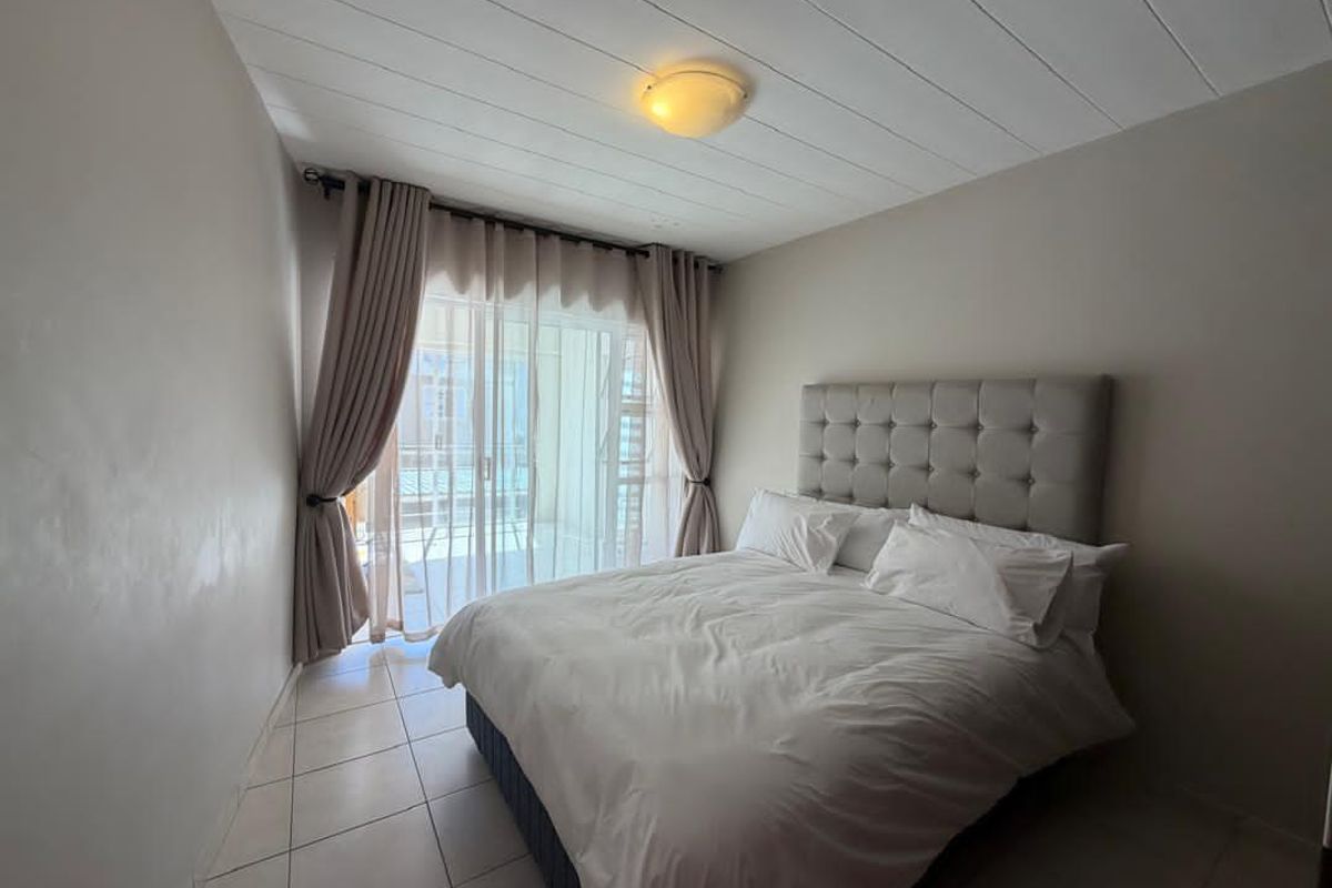 A bedroom featuring tiled flooring, a paneled ceiling, and sliding glass doors that provide access to an outdoor balcony area.