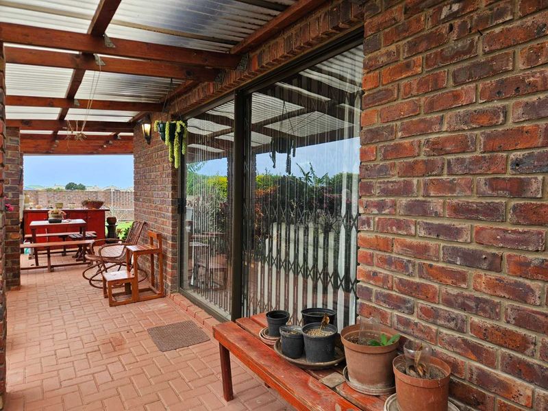 Covered outdoor patio featuring exposed brick walls, timber pergola structure, and paved flooring, providing a functional space for outdoor relaxation.