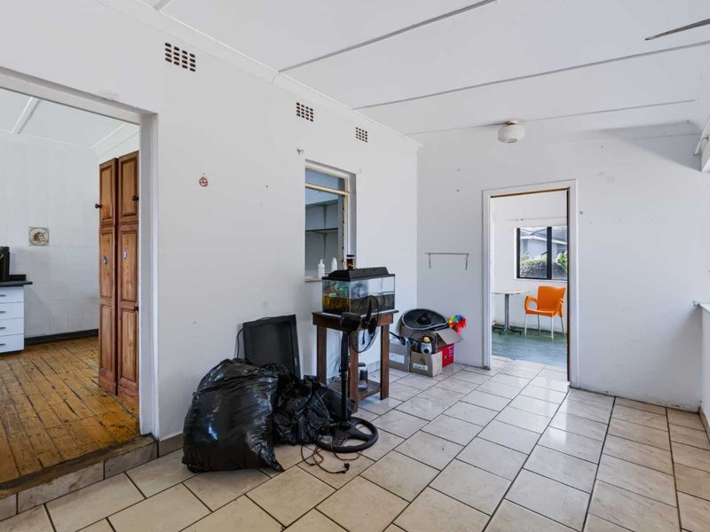 A functional living area featuring tiled flooring and direct access to adjacent rooms, offering a blank canvas for renovation and interior design updates.