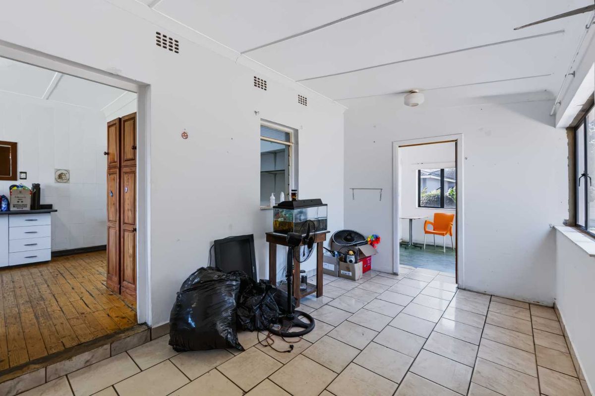 A functional living area featuring tiled flooring and direct access to adjacent rooms, offering a blank canvas for renovation and interior design updates.