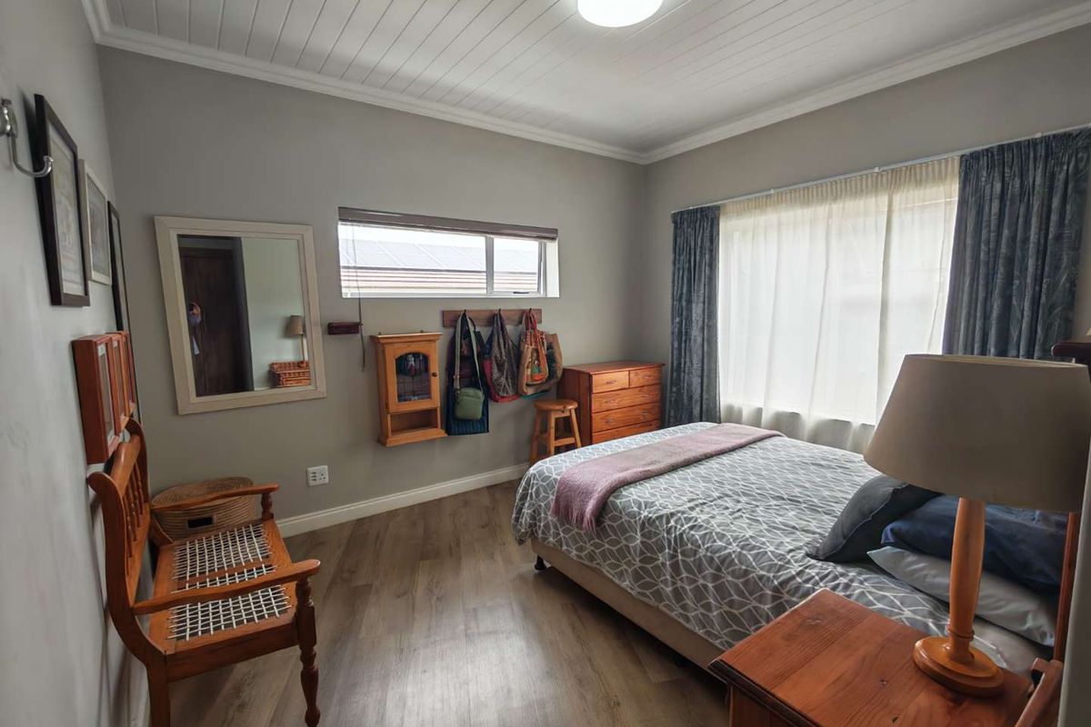 A well-maintained bedroom featuring wood-look flooring, a tongue-and-groove ceiling, and large windows that provide ample natural light.