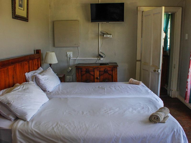A bedroom featuring a wooden door, wall-mounted television, and visible electrical wiring. The room requires cosmetic updates to improve its overall condition and appeal.