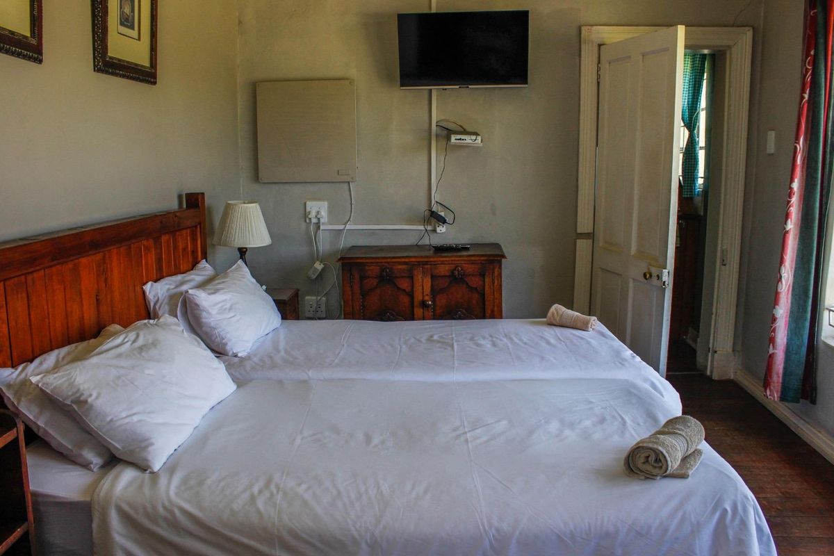 A bedroom featuring a wooden door, wall-mounted television, and visible electrical wiring. The room requires cosmetic updates to improve its overall condition and appeal.
