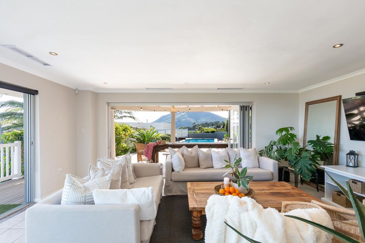 Spacious living room featuring recessed lighting, ducted air conditioning, and large stacking glass doors that open onto a patio with pool and mountain views.