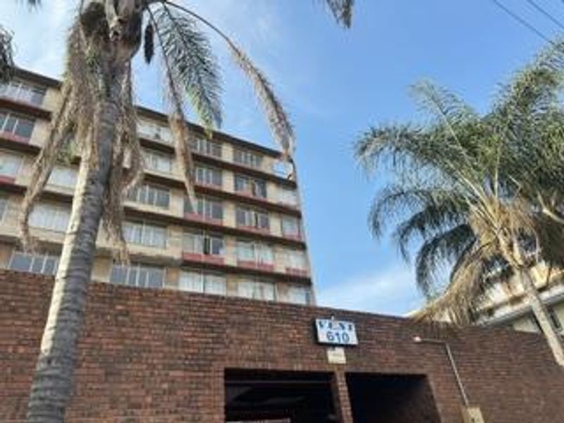 Exterior view of a multi-story apartment building featuring a brick facade and balcony levels.