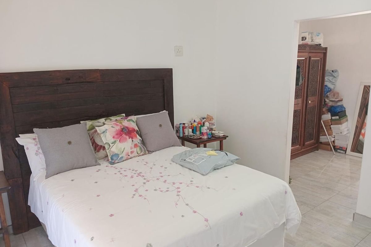 A bedroom featuring tiled flooring and a doorway leading to an adjacent dressing or storage area.