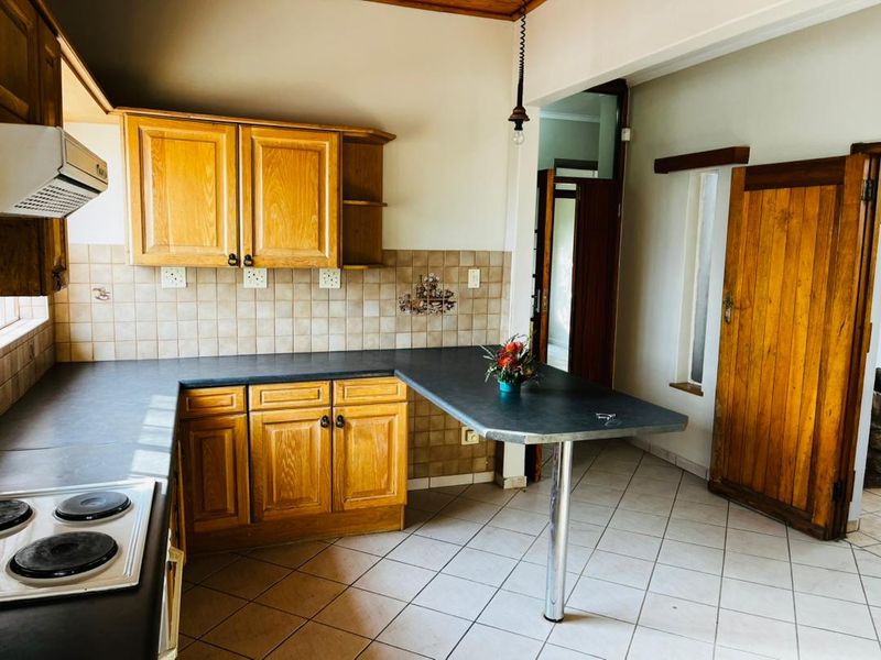A functional kitchen featuring wooden cabinetry, a breakfast bar, ceramic tile flooring, and a tiled backsplash, offering a classic layout with potential for modernization.