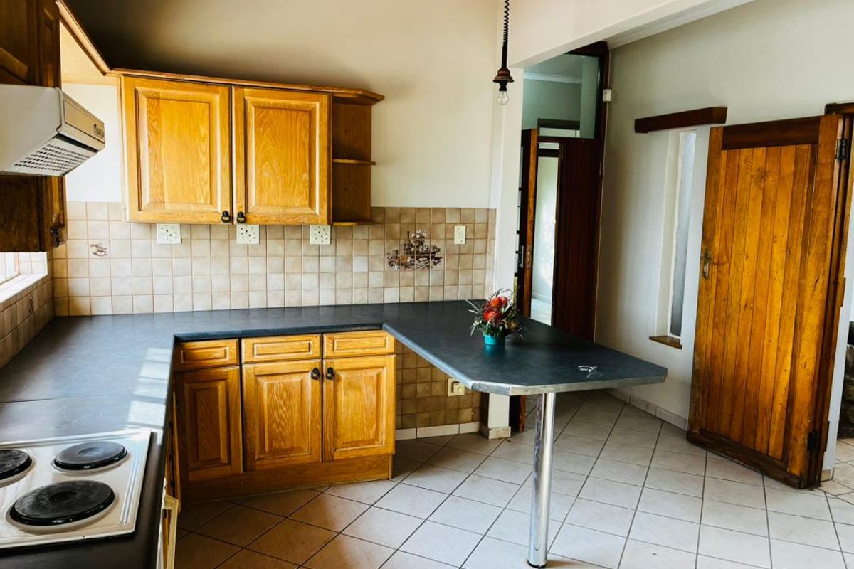 A functional kitchen featuring wooden cabinetry, a breakfast bar, ceramic tile flooring, and a tiled backsplash, offering a classic layout with potential for modernization.
