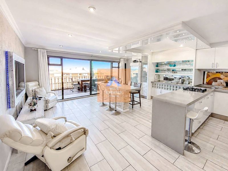 Modern open-plan living and kitchen area featuring tiled floors, a central island, sleek cabinetry, and large sliding doors leading to an outdoor patio.