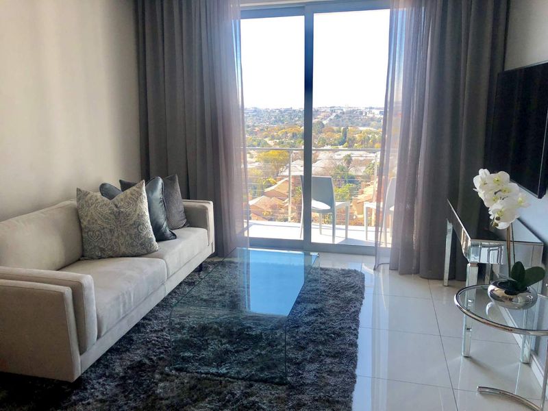 Modern living room featuring large sliding glass doors that open onto a balcony, providing ample natural light and scenic views.