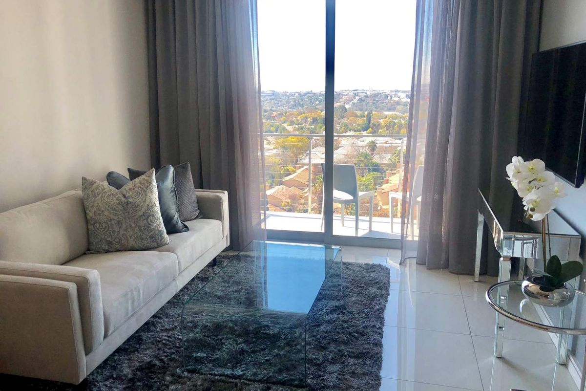Modern living room featuring large sliding glass doors that open onto a balcony, providing ample natural light and scenic views.