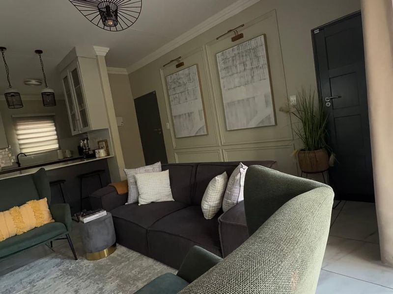 An open-plan living and kitchen area featuring modern wall paneling, tiled flooring, and a functional kitchen island with pendant lighting.