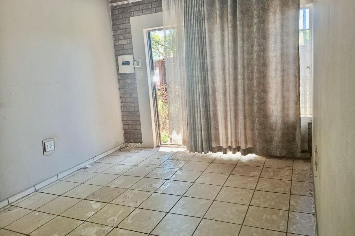 A vacant room featuring tiled flooring, a brick feature wall, and a sliding glass door providing access to the exterior.