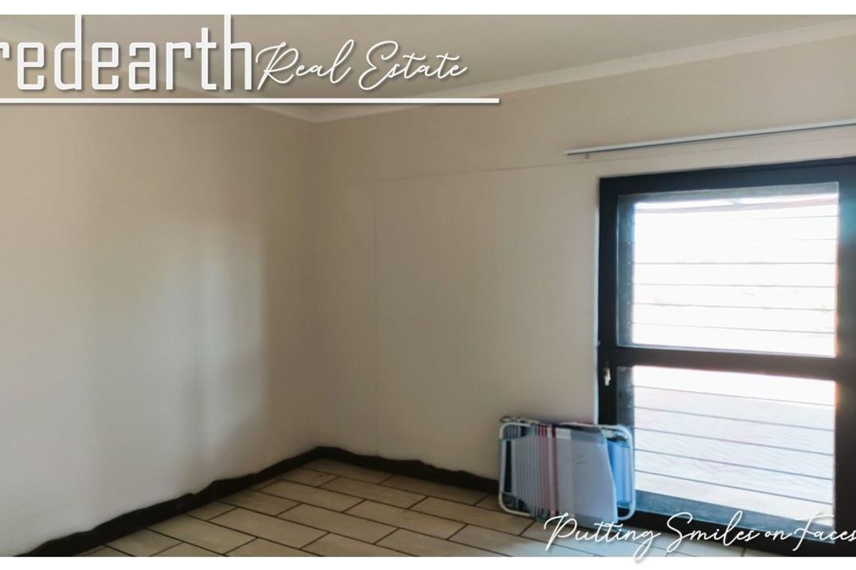 A vacant bedroom featuring tiled flooring and an aluminium framed door with security gate, providing access to the exterior.